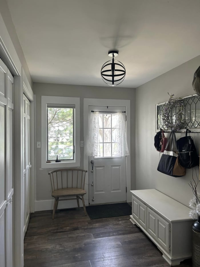 A entryway for a house with a chair and a bench